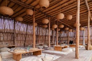 Habitación grande con mesas de madera y cestas en el techo. en Alkamar Camp Agafay en El Karia