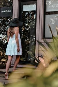 Ein kleines Mädchen mit einem Hut, das auf einer Veranda steht. in der Unterkunft Bella Bungalows in Punta Del Diablo