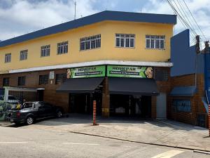 a building with a car parked in front of it at Hostel Lize in Cumbica
