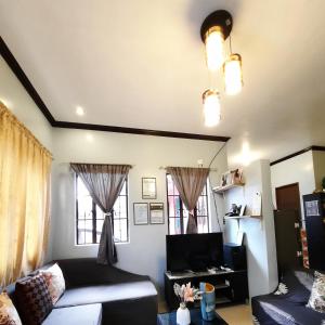 a living room with a bed and two windows at Angel's Place Transient House in Tagbilaran City