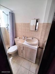 ein Badezimmer mit einem Waschbecken, einem WC und einem Spiegel in der Unterkunft La mejor ubicación de Arica in Arica