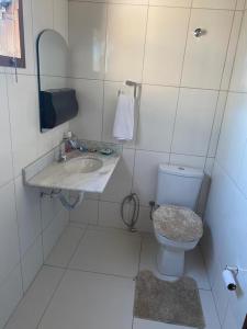 a white bathroom with a toilet and a sink at Casa grande e bela in Porto Seguro