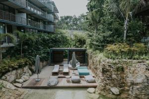 a resort patio with umbrellas and chairs in the water at Cenote + Swim-Up + Luxury Condo in Tulum