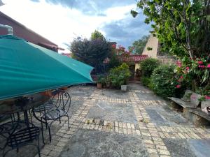 un patio con una mesa y una sombrilla verde en La Viña - Sogamoso en Sogamoso