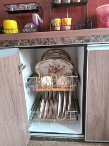 a kitchen cabinet with plates and utensils in it at Narayana Illam in Nilai