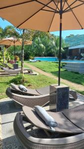 a row of lounge chairs with an umbrella at Becano Restobar and Resort in Siquijor