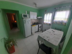Una cocina con una mesa y un refrigerador blanco. en Departamento América, en Puerto Madryn