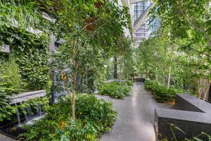 a walkway in a building with benches and trees at Paragon Apartments by CLLIX in Melbourne