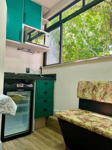 uma pequena cozinha com armários verdes e uma janela em Mar Rio casa de praia em Piçarras