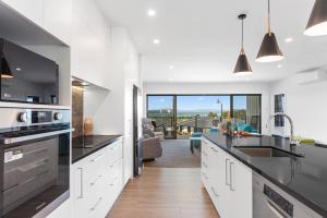 a kitchen with white cabinets and a view of a living room at Blue Dun Views - Taupo in Taupo