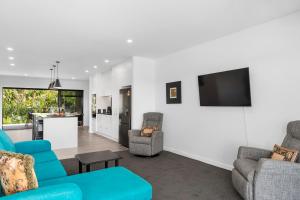 uma sala de estar com duas cadeiras azuis e uma televisão em Blue Dun Views - Taupo em Taupo