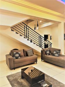 a living room with two couches and a staircase at Entire Serviced Two bedroom duplex Abuja - 24hr WIFI, POWER, OFFICE, FULL KITCHEN in Abuja