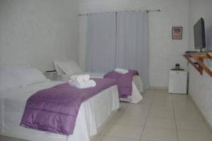 a bedroom with two beds with purple sheets and towels at Black Hotel in Bauru