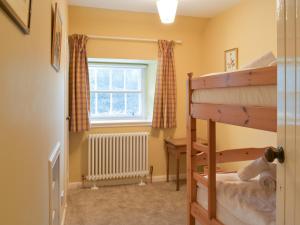 a bedroom with a bunk bed and a window at Wanton Was Cottage in Penicuik