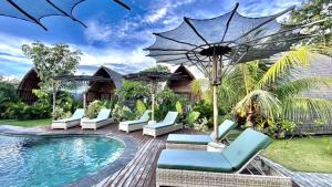 a resort pool with lounge chairs and an umbrella at Lumbung Bukit Resort Uluwatu in Uluwatu