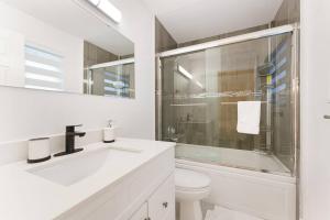 a white bathroom with a shower and a toilet at Luxury Home In Burnaby/Metrotown/SFU in Burnaby