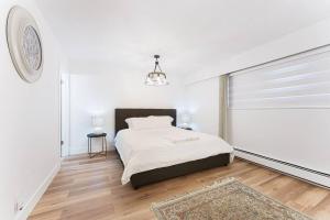 a white bedroom with a bed and a window at Luxury Home In Burnaby/Metrotown/SFU in Burnaby