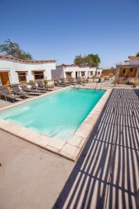 a large swimming pool with chairs at Hotel La Cochera in San Pedro de Atacama