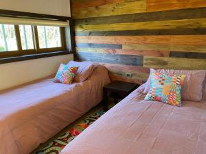 two beds in a room with wooden walls at Cabaña Pampa Pinuer Coyhaique in Coihaique