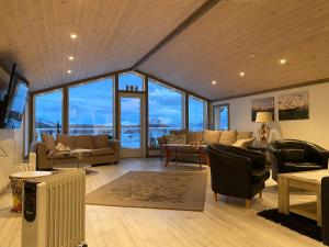 a living room with couches and chairs and windows at In the heart of the Lyngen alps, Holmen i Lyngen in Lyngseidet