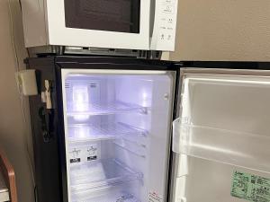 a refrigerator with its door open and a microwave above it at The Guest House Noah in Naha
