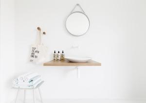 ein weißes Badezimmer mit einem Holzregal und einem Spiegel in der Unterkunft Logieslogees in Tielrode