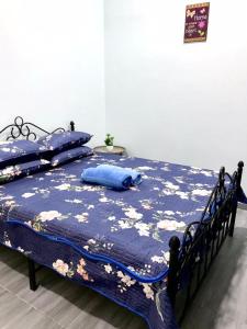 1 cama con edredón azul y almohadas azules en Teratak Ar-Rayyan x Villa Abi, en Batu Kurau