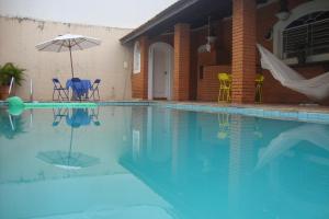 a swimming pool with chairs and an umbrella next to a house at Black Hotel in Bauru