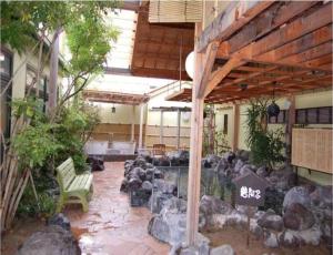 un patio avec un étang, un banc et des rochers dans l'établissement Yuzenkyo, à Kyoto