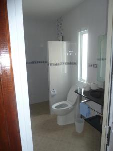 a white bathroom with a toilet and a window at Gib Apartment in Surin