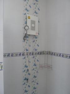 a shower in a bathroom with a machine on the wall at Gib Apartment in Surin