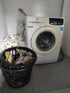 einen Wäschekorb neben einer Waschmaschine in der Unterkunft UB HOME in Dauis