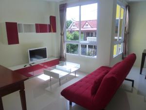 a living room with a red couch and a tv at Gib Apartment in Surin