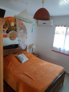 a bedroom with a bed with an orange blanket at Villa Les Flambloyants in Baréto