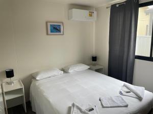 a bedroom with a white bed with two towels on it at Lakes Main Holiday Park in Lakes Entrance