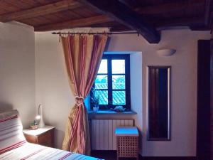 a bedroom with a bed and a window at Altes Backhaus in Maranzana in Mombaruzzo