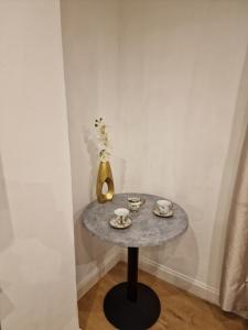 un tavolo con vaso, tazze e piattini sopra di Cosy Studio Apartment In FULHAM a Londra