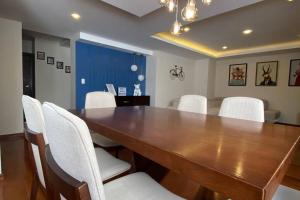 a dining room with a wooden table and white chairs at Penthouse Lujoso y moderno en el centro de Riobamba - Wanderlot Leganza in Riobamba