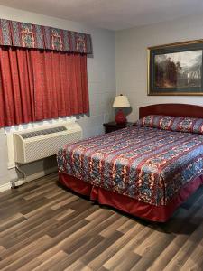 1 dormitorio con cama, radiador y cortinas rojas en Arrow Lake Motel en Fauquier