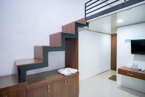 a living room with a staircase and a television at RedDoorz at Jalan Basuki Rahmat Lampung in Lampung