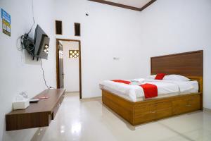 a bedroom with a bed and a desk and a tv at RedDoorz at Jalan Basuki Rahmat Lampung in Lampung