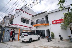 Lampung的住宿－RedDoorz at Jalan Basuki Rahmat Lampung，停在大楼前的白色汽车