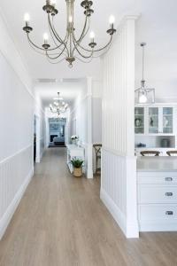 un pasillo blanco con una lámpara de araña en una casa en River Hamptons, en Berri