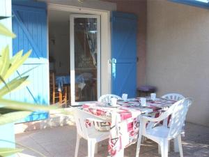 stół z białymi krzesłami i niebieskimi drzwiami w obiekcie Maison cosy avec terrasse, 2 chambres, piscine partagée, proche plage et commerces, Gruissan - FR-1-229-832 w mieście Gruissan