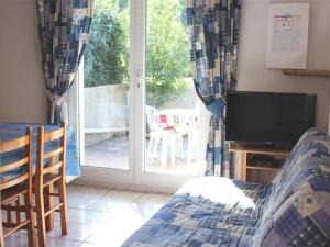 salon z telewizorem i przesuwnymi szklanymi drzwiami w obiekcie Maison cosy avec terrasse, 2 chambres, piscine partagée, proche plage et commerces, Gruissan - FR-1-229-832 w mieście Gruissan
