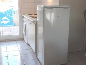 biała lodówka w kuchni obok zmywarki w obiekcie Maison cosy avec terrasse, 2 chambres, piscine partagée, proche plage et commerces, Gruissan - FR-1-229-832 w mieście Gruissan +4 zdjęcia