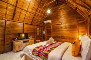 um quarto com paredes de madeira, uma cama e uma televisão em The Tukad Gepuh Cottage and Resto em Nusa Penida