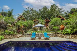 uma piscina de resort com duas cadeiras e um guarda-sol em The Tukad Gepuh Cottage and Resto em Nusa Penida