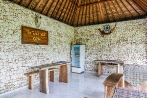 a room with a refrigerator and a table and chairs at The Tukad Gepuh Cottage and Resto in Nusa Penida
