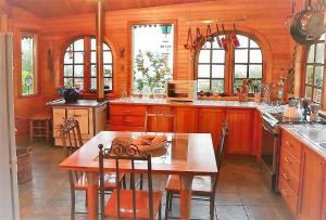 una cocina con armarios de madera y una mesa con sillas. en Casa La Montaña, en San José de Maipo